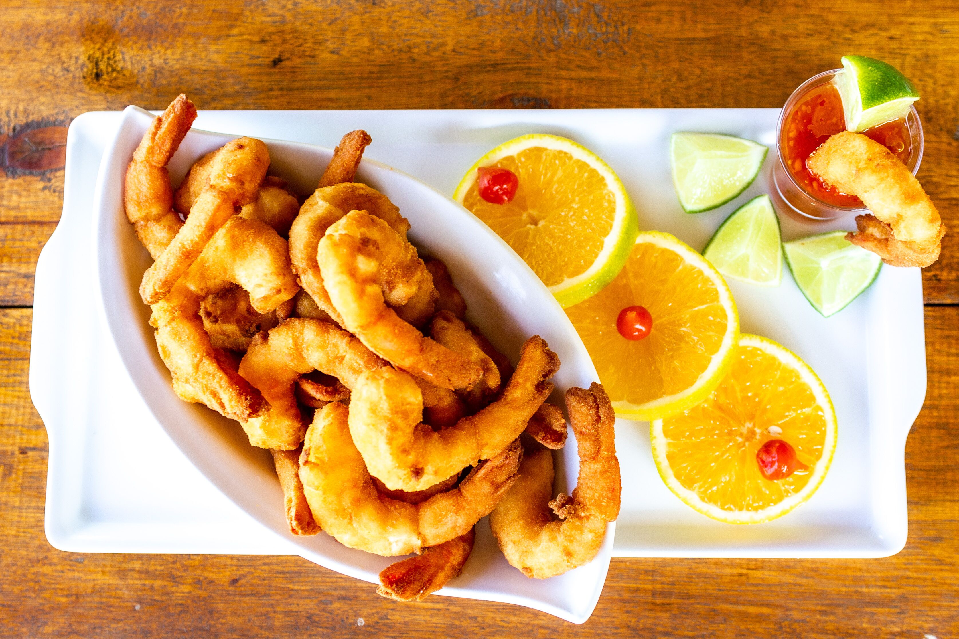 Un plato de calamares fritos con gajos de limón y una taza pequeña de salsa.