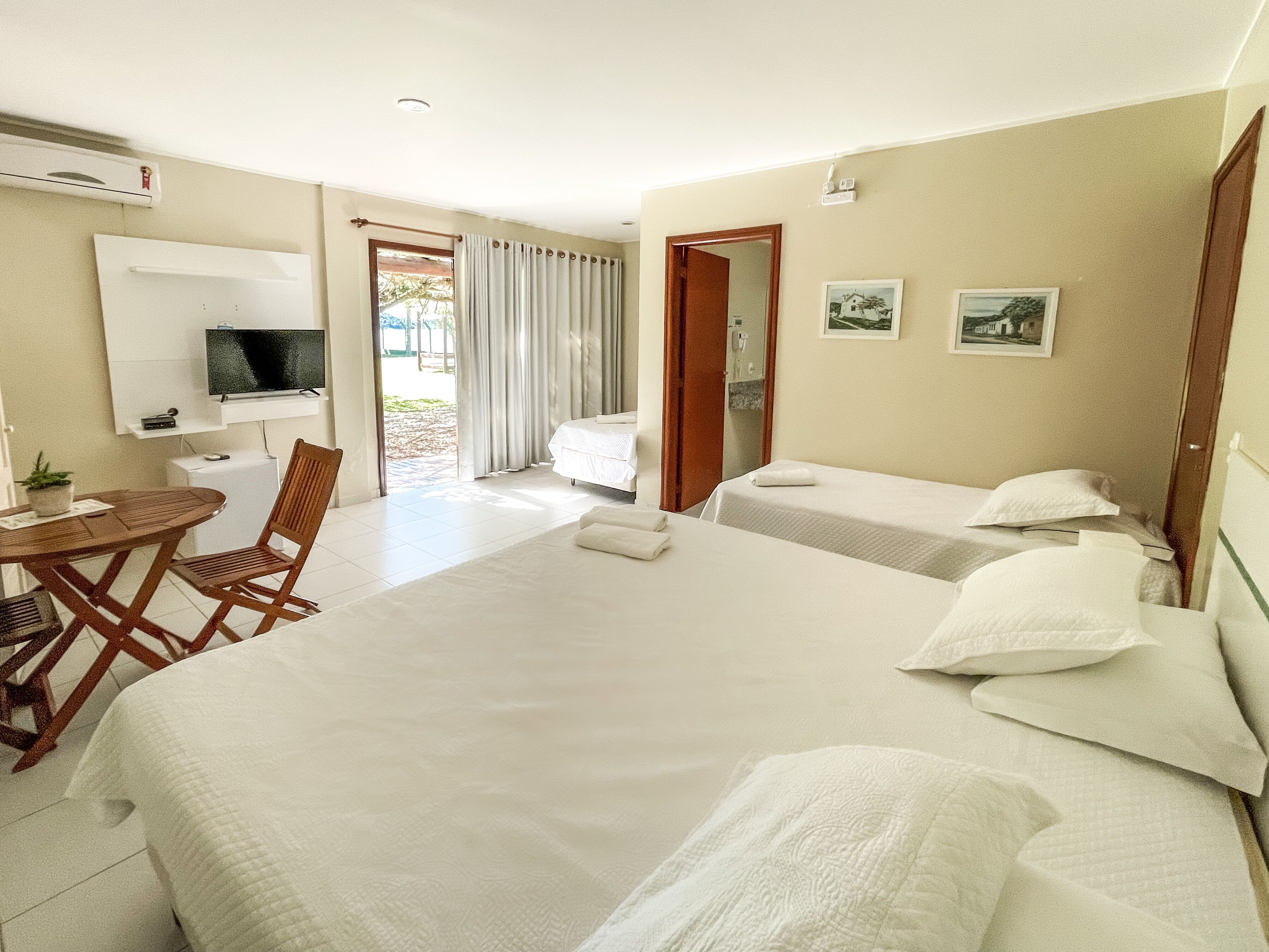 A hotel room with two beds, a desk, a chair, a TV, and a window with curtains.