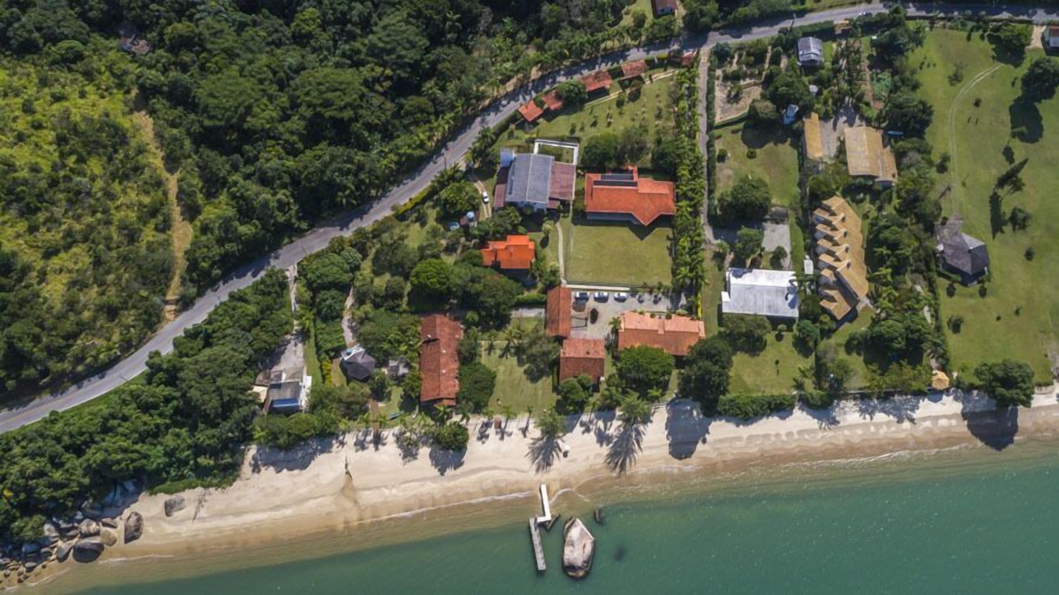 An aerial view of a coastal property with a beach, a marina, and a mix of residential buildings.