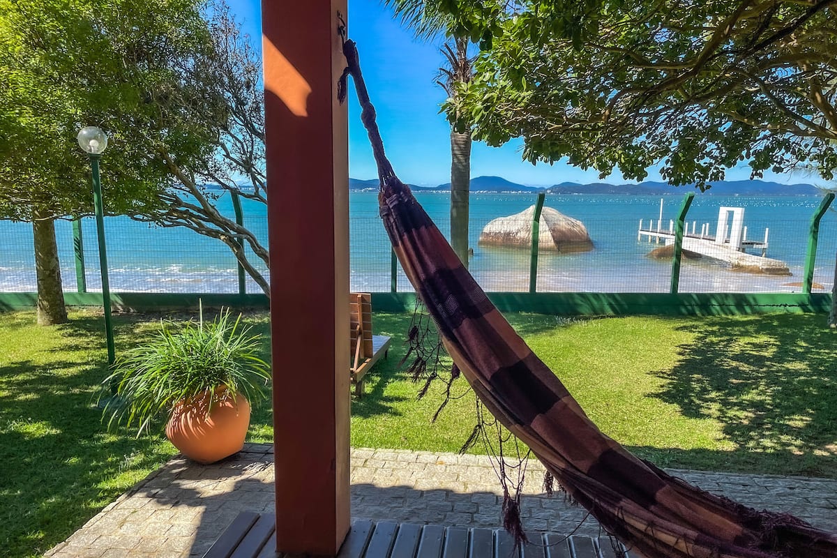 A hammock on a wooden deck overlooking a body of water with a view of distant mountains.