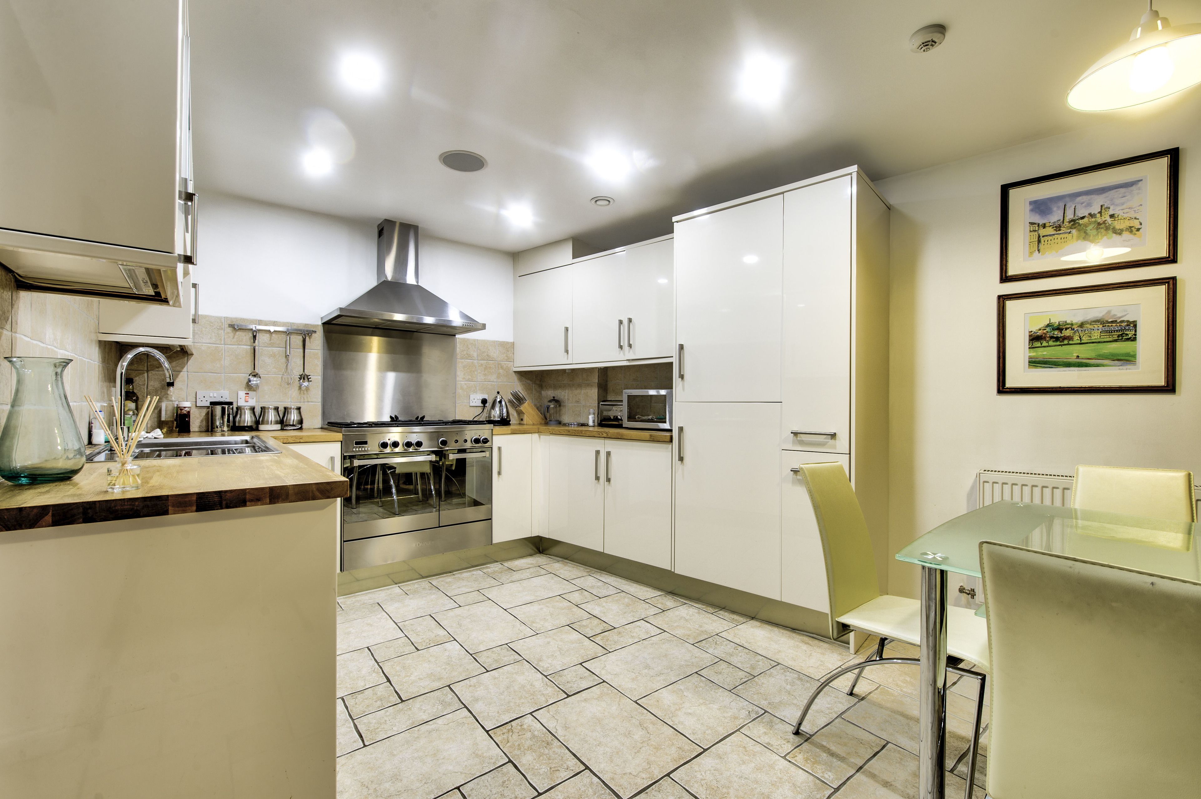 A modern kitchen with white cabinets, stainless steel appliances, and a tiled floor.