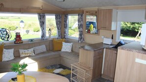 A compact living space with a sofa, a dining table, and a kitchen area. - Melorne Farm (Camelford)
