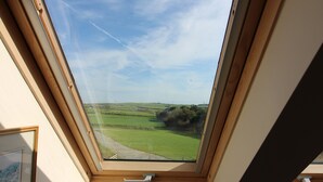 A skylight with a view of a green landscape. - Melorne Farm (Camelford)