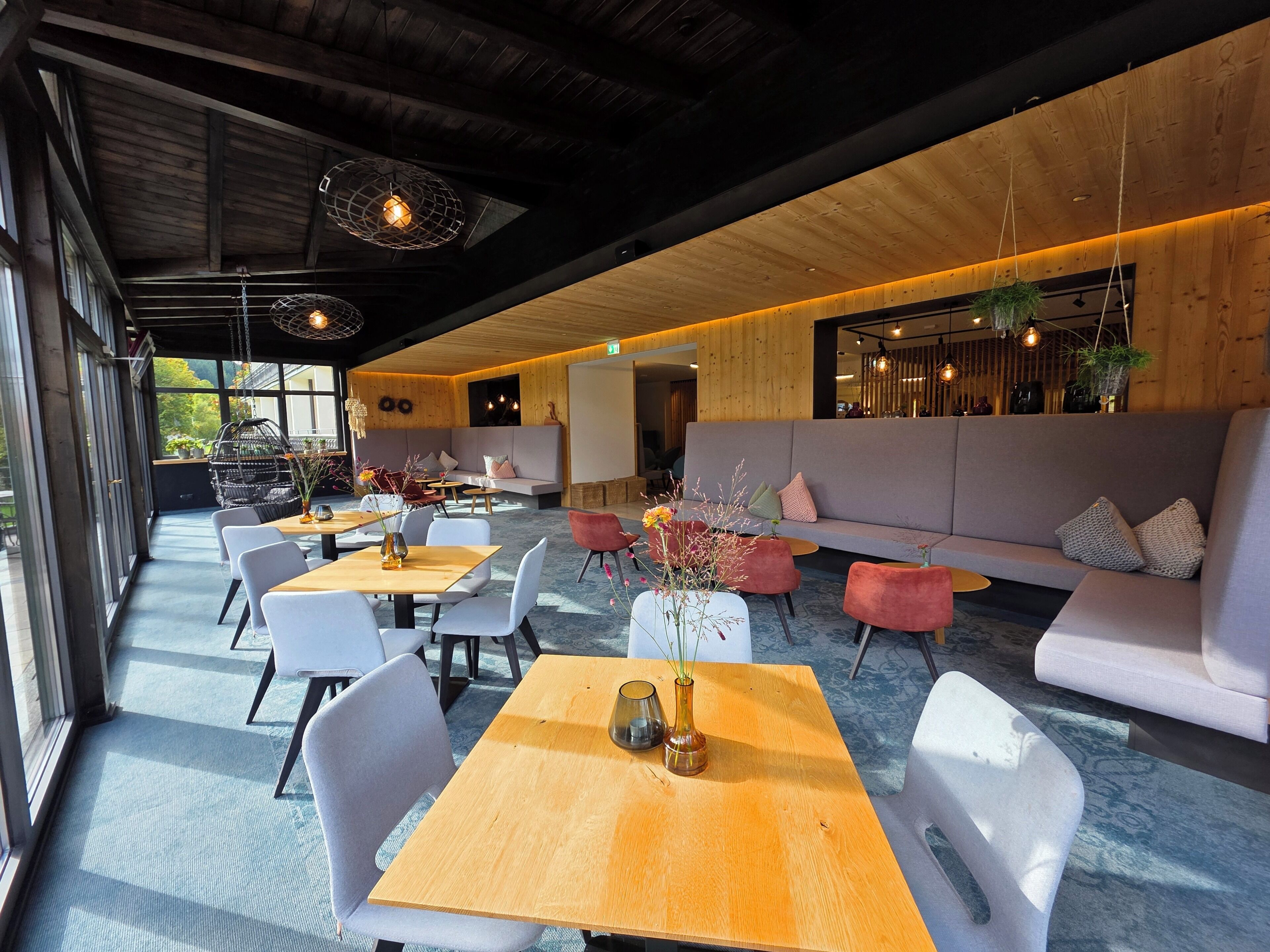 A modern interior with a wooden ceiling, seating areas, and hanging lights.