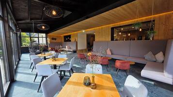 A modern interior with a wooden ceiling, seating areas, and hanging lights.