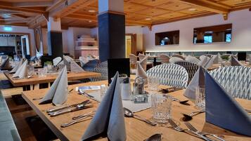 Un restaurante con mesas de madera dispuestas para comer, con servilletas, cubiertos y vasos.
