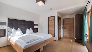 Un dormitorio moderno con una cama de madera, cabecera con lámpara y mesita de noche, además de un armario.