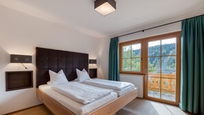 Un dormitorio moderno con una cama grande, dos mesitas de noche, un cabecero y un ventanal con vistas a un bosque y una carretera.