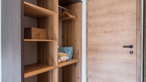 Un vestidor con estantes de madera, una barra para colgar ropa y una puerta.