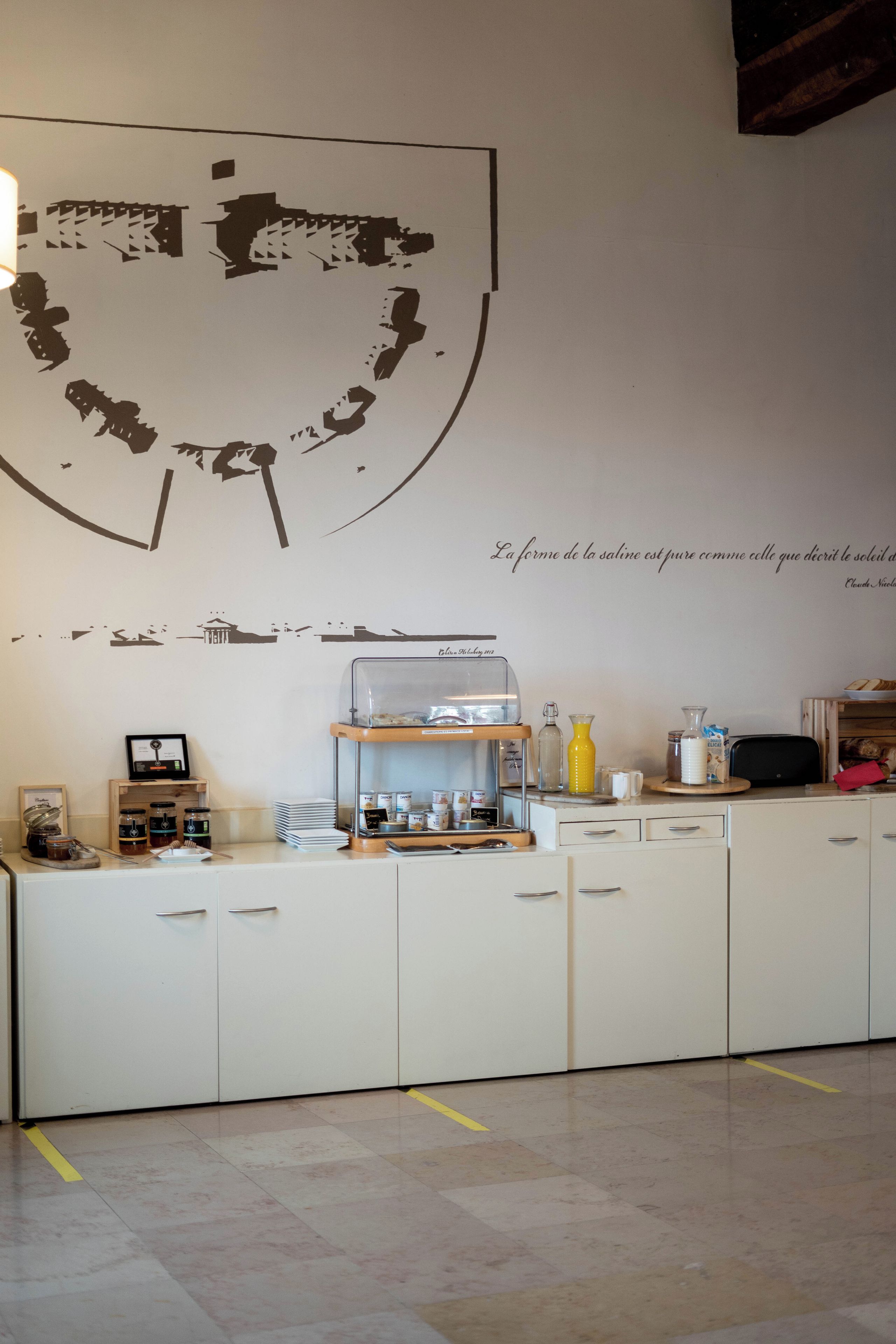 A kitchen with a large wall art piece, a coffee station, and a wooden cabinet.