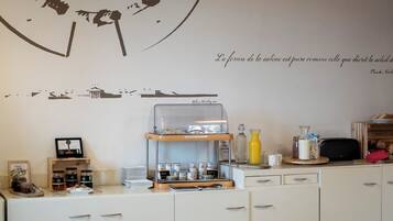 A kitchen with a large wall art piece, a coffee station, and a wooden cabinet.