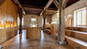 A rustic interior with wooden beams, a central island, and a stone wall.