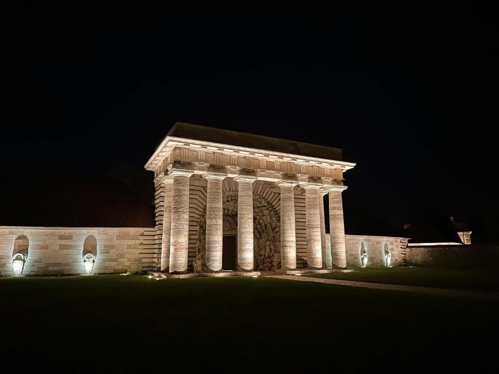 A large, illuminated building with a classical architectural style, featuring a prominent entrance with columns and a portico.