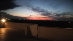 A rooftop with a view of the sky at dusk, featuring clouds and distant city lights. - Agriturismo Monte Adamo (Conversano)