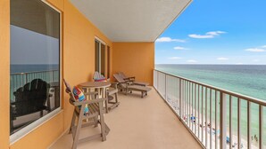 A balcony with a view of the ocean, wooden furniture, and a railing.
