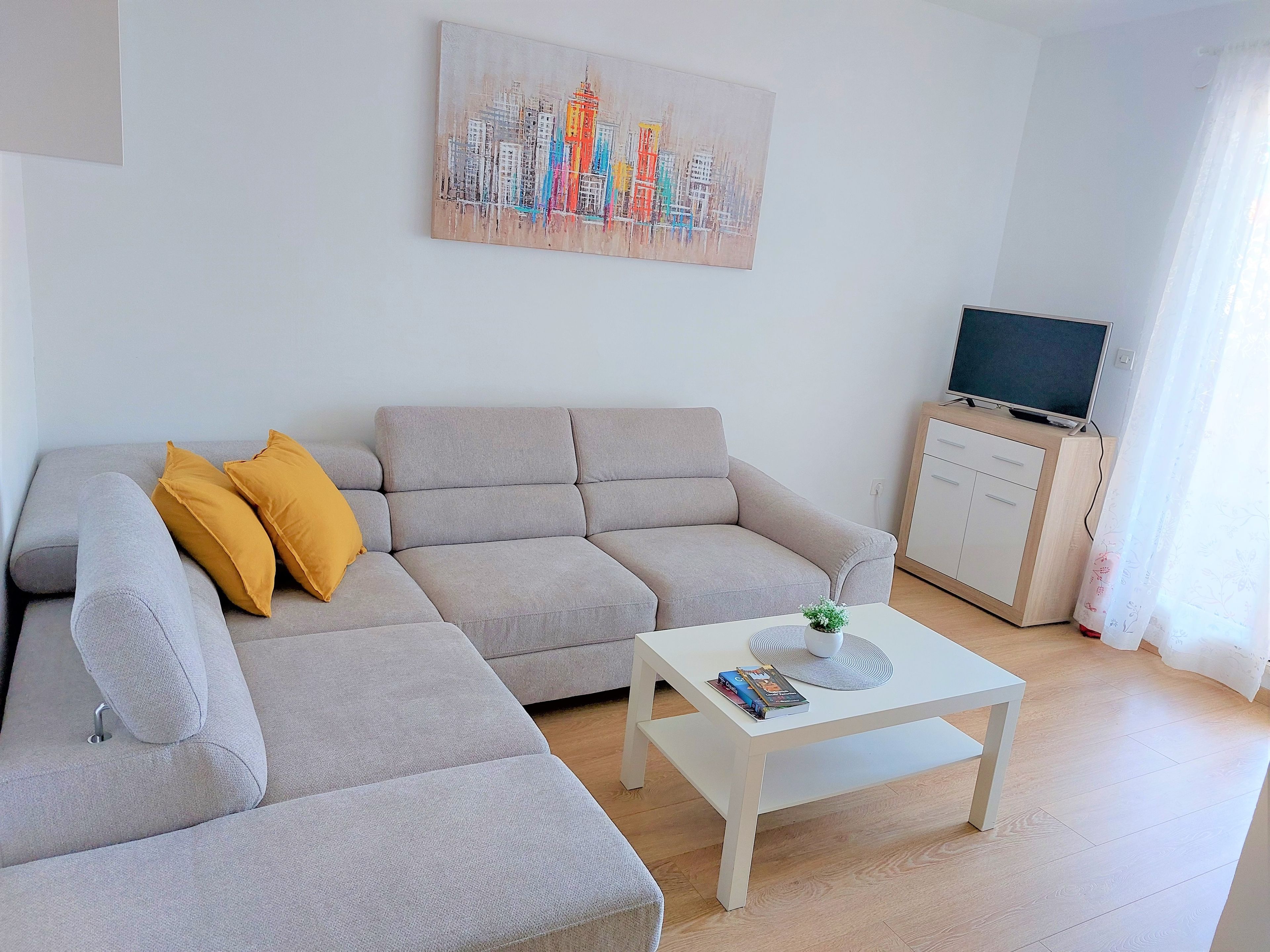 Un salón con un sofá, una mesa de centro, un televisor y un cuadro en la pared.