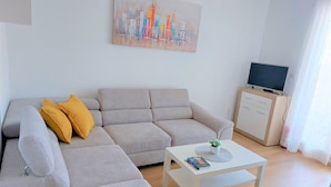 A living room with a sofa, a coffee table, a TV, and a painting on the wall.