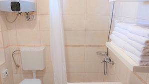 A bathroom with a toilet, shower, and a sink with a towel rack.