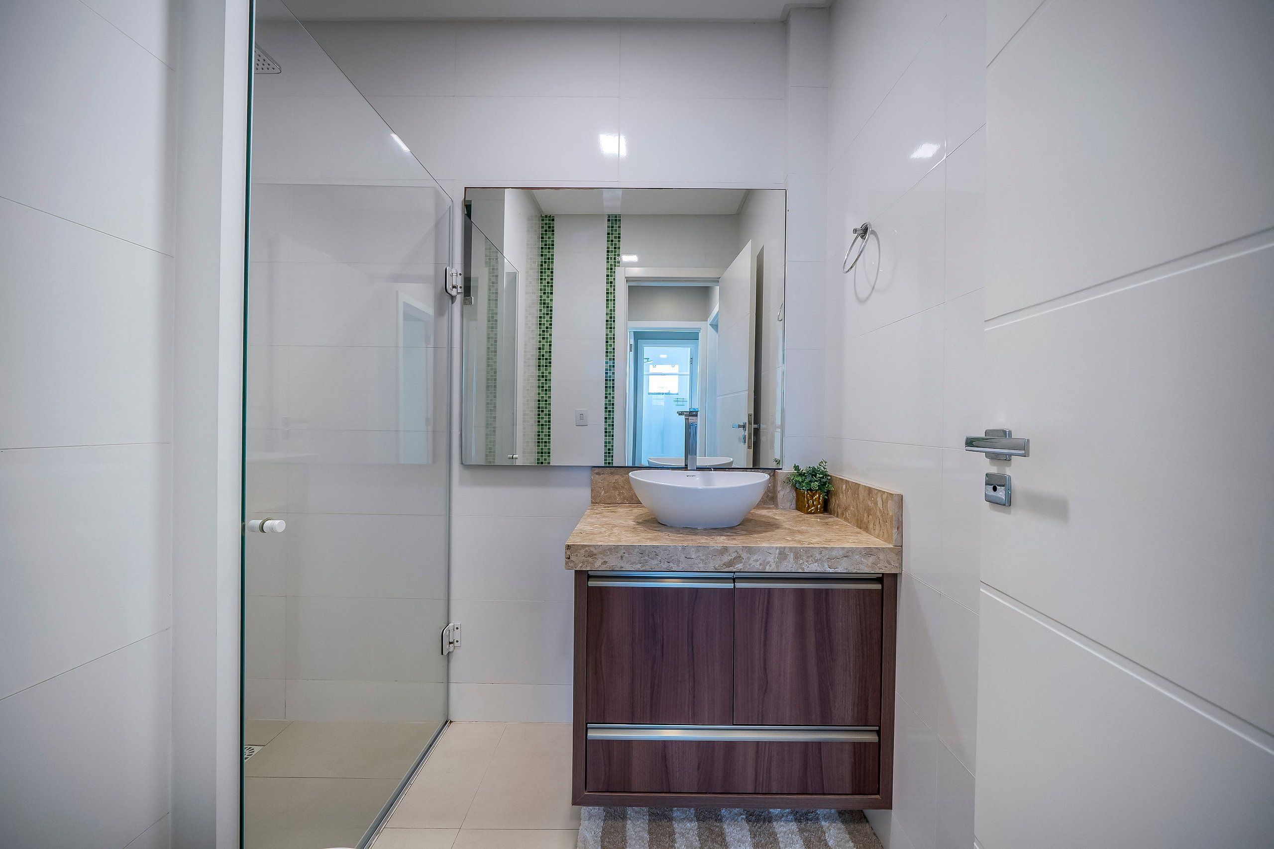 A modern bathroom with a glass shower enclosure, a large mirror, a vessel sink, and a wooden vanity.