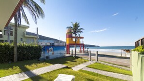 A beachside view with a colorful building, a palm tree, and a white lounge chair.