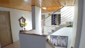 Una escalera que sube a un segundo piso, una zona de cocina con encimera de madera y un cuadro en la pared.
