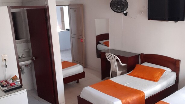 Una habitación de hotel con dos camas, un escritorio, una silla, un televisor y un baño.