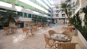 A courtyard with outdoor seating, a pool, and modern buildings. - Aluguel Apartamento 1 quarto Summer Beach 076A (Bombinhas)