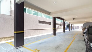 Un garaje para estacionar con pilares de concreto, líneas amarillas y un automóvil estacionado.