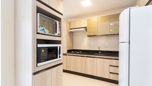 Una cocina moderna con electrodomésticos integrados, armarios de madera y encimera negra.