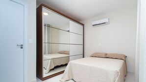 Un dormitorio con cama, espejo y equipo de aire acondicionado.