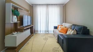 Una sala de estar moderna con un sofá, televisor y plantas decorativas.