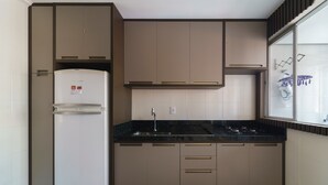 Una cocina compacta con refrigerador, pileta y estufa.