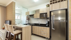 Een moderne keuken met houten kastjes, een roestvrijstalen koelkast en een barruimte met twee comfortabele stoelen.