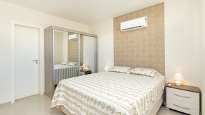Een slaapkamer met een bed, nachtkastjes, een kledingkast en een airconditioning.