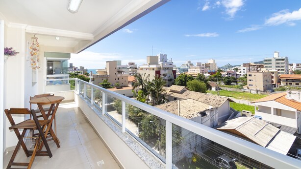 Een balkon met een tafel en stoelen, met uitzicht op een stadsgezicht met verschillende gebouwen en een heldere lucht.