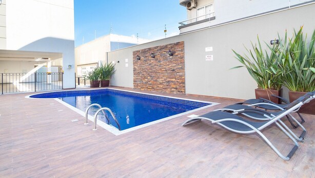 Una piscina amb una terrassa de fusta, gandules i plantes en testos.