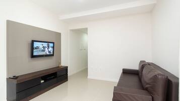 Uma sala de estar moderna com televisão de tela plana na parede, um sofá marrom escuro e um móvel de entretenimento elegante.