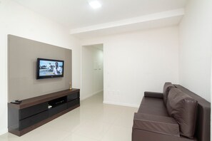 Una sala de estar moderna con un televisor de pantalla plana montado en la pared, un sofá marrón oscuro y un mueble de entretenimiento elegante.