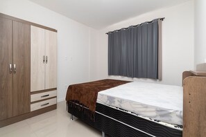 Une chambre à coucher avec un lit, une armoire et une fenêtre avec des rideaux.