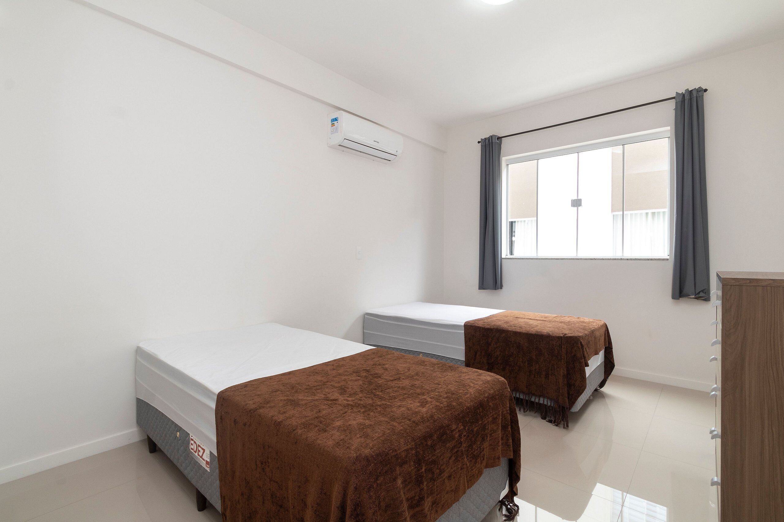 Une chambre avec deux lits, une armoire et une fenêtre avec des rideaux.