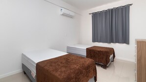 Una habitación con dos camas, un armario de madera y un aire acondicionado.
