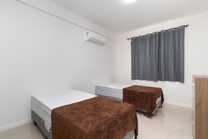 Une chambre avec deux lits, une armoire en bois et un appareil de climatisation.
