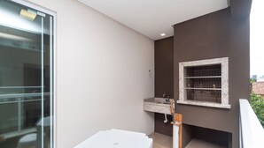 Un balcón con una mesa blanca, un lavamanos pequeño y una ventana con una repisa.