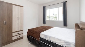 Un dormitori amb un llit, un armari, una finestra amb cortines i vista a l'exterior.