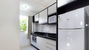 Une cuisine moderne avec des armoires blanches, un comptoir noir, un four à micro-ondes encastré, une cuisinière et un réfrigérateur blanc.