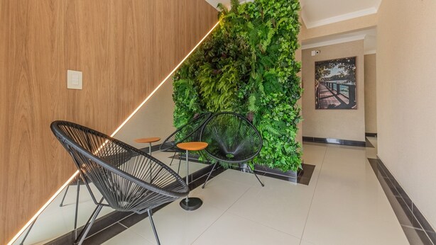 Un intérieur moderne avec un mur en bois, un jardin vertical verdoyant et des chaises à structure métallique noire, accompagnées de tabourets en bois.