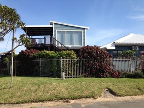 A two-story house with a balcony, a fenced yard, and a clear sky. - Ocean Dreams Bed & Breakfast (East London)