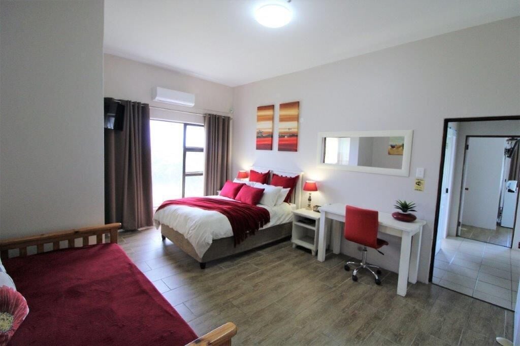 A hotel room with a bed, bedside tables, a desk, and a chair.