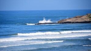 A coastal scene with waves crashing against a rocky shore under a clear sky. - Cove View Bed & Breakfast (East London)