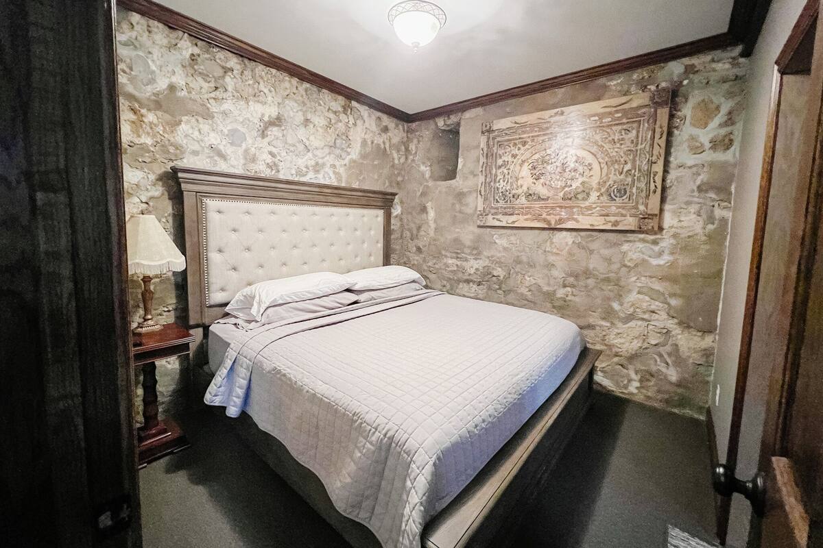 Ein Schlafzimmer mit einem großen Bett, einem Nachttisch, einer Lampe und einem Wanddekor.